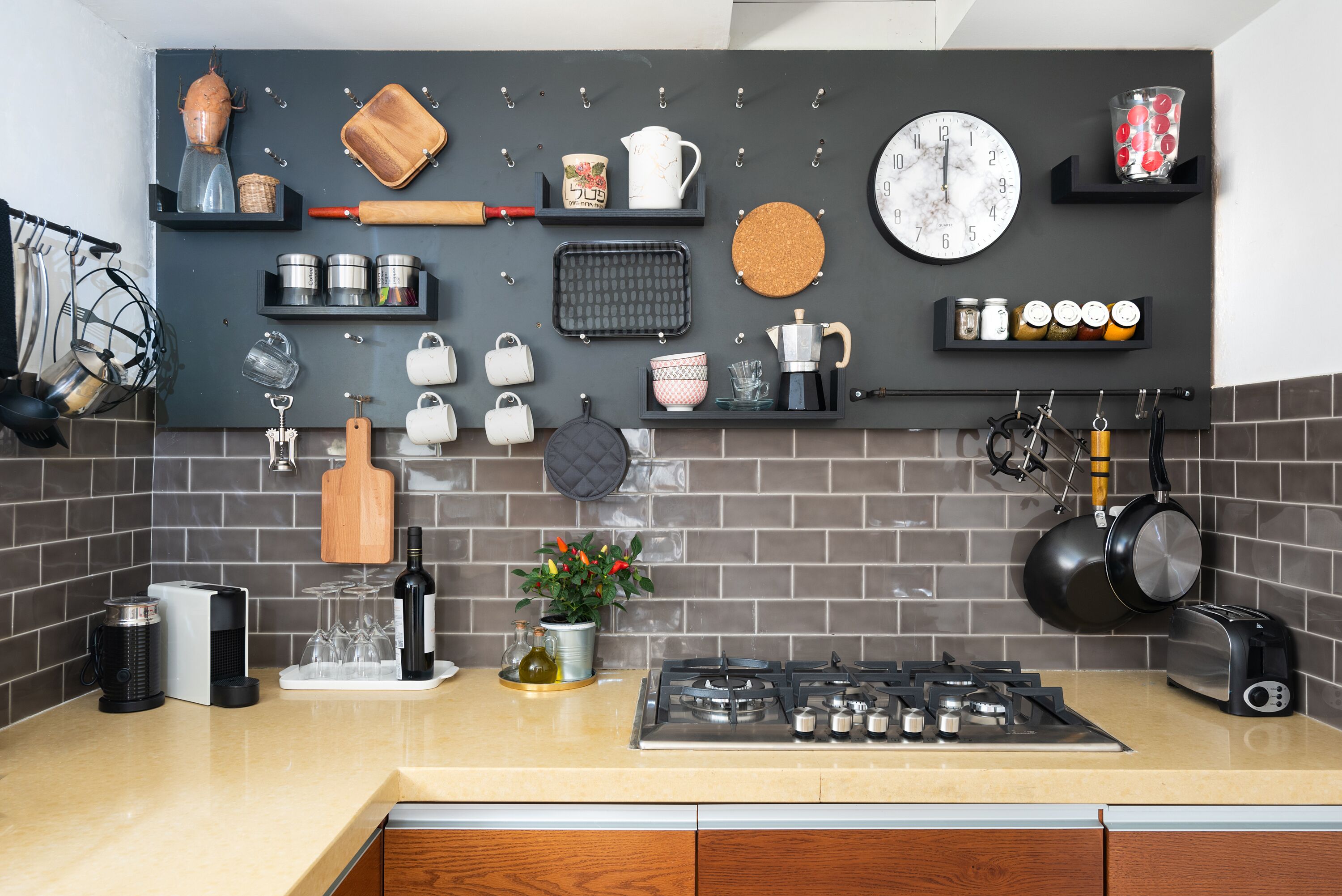 Una cucina moderna con piano cottura a gas, diversi utensili da cucina, una sveglia e una macchina per il caffè.