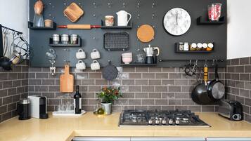 Una cucina moderna con piano cottura a gas, diversi utensili da cucina, una sveglia e una macchina per il caffè.