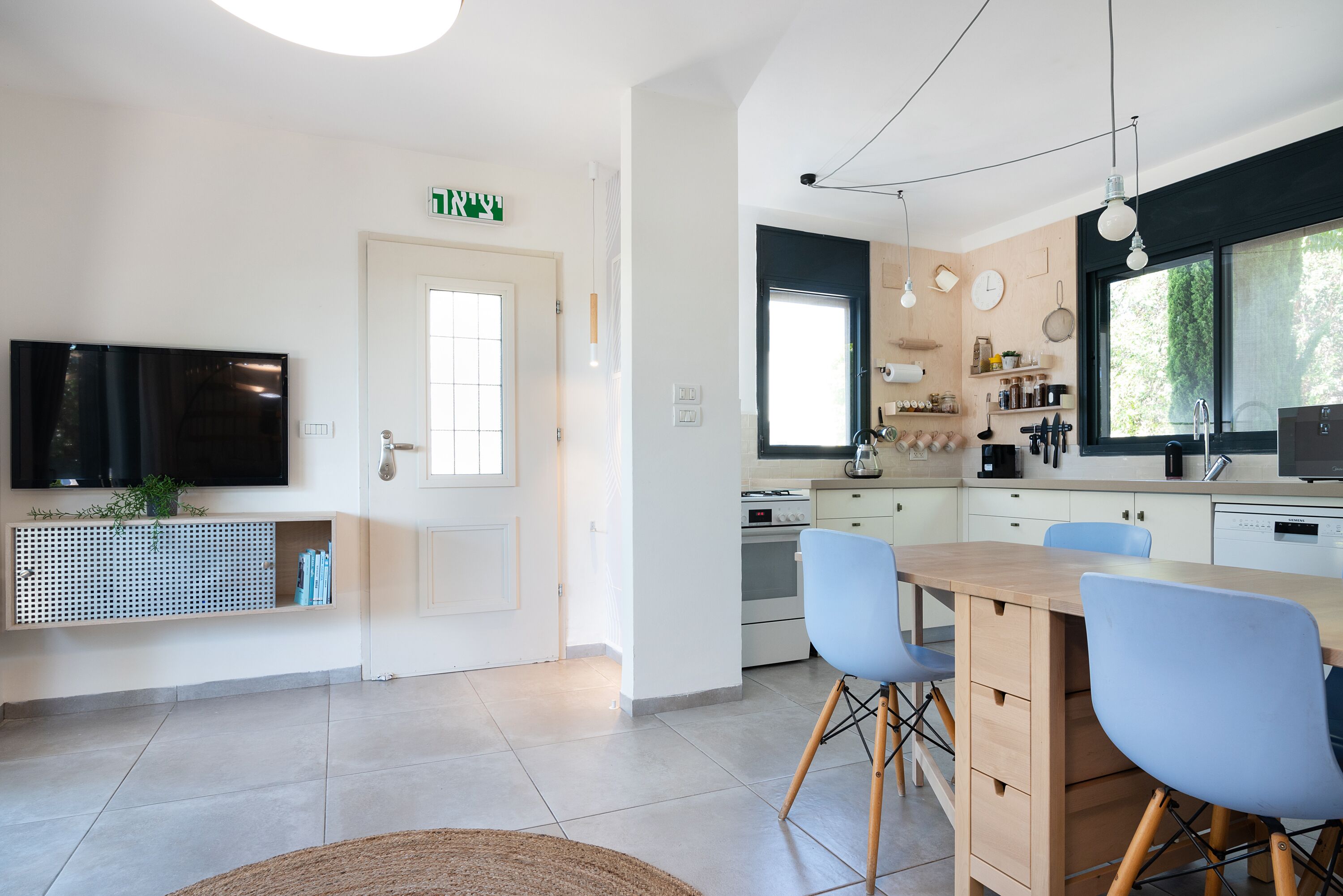 Una cocina moderna con comedor, televisor y puerta con ventana.