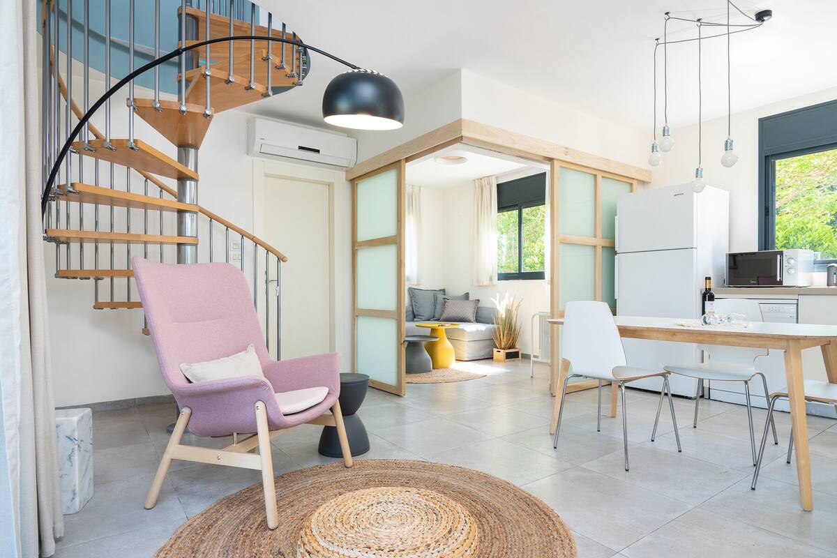 A modern kitchen with a built-in oven, a dining area with a wooden table, and a staircase with a unique design.
