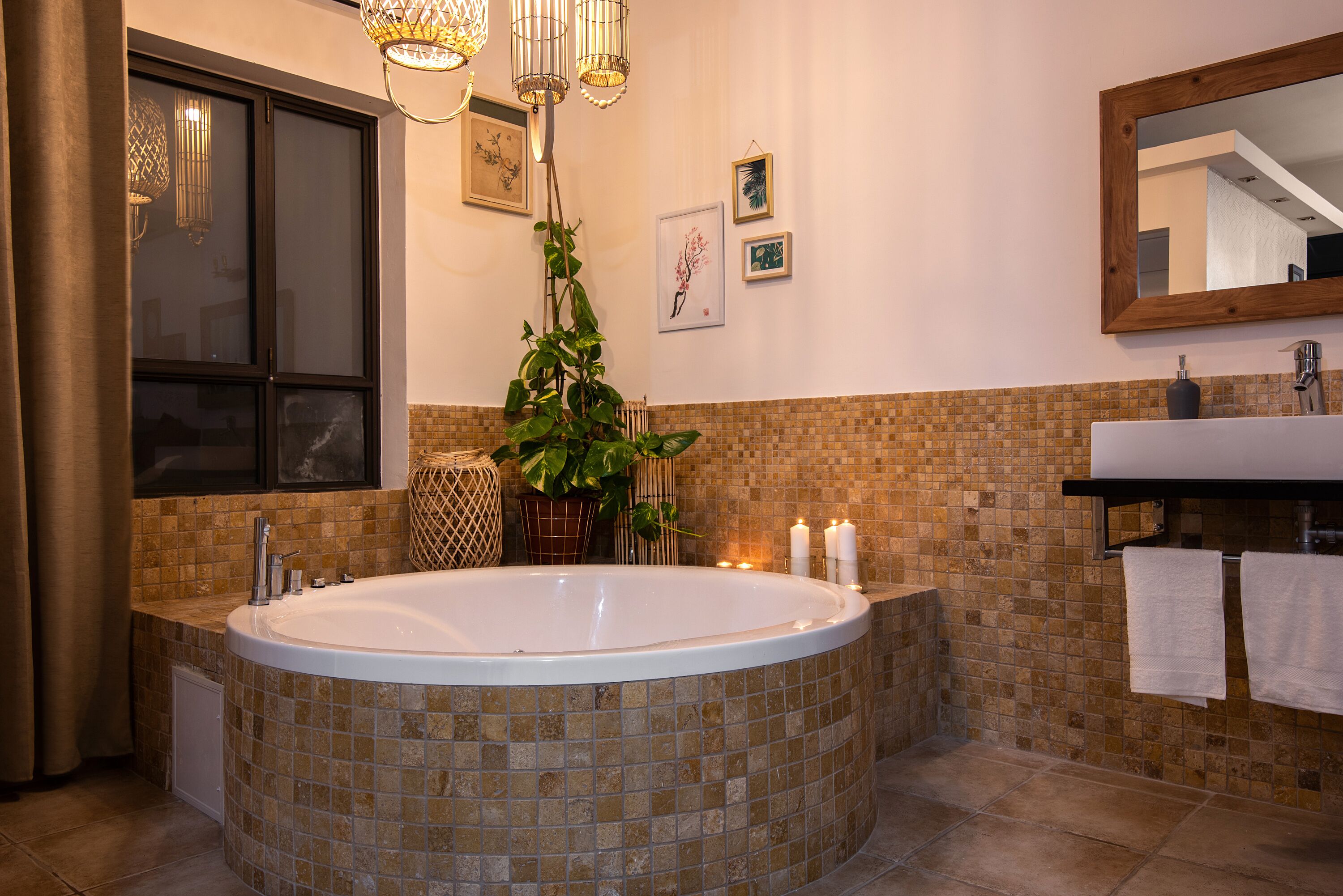 Une salle de bain moderne avec une baignoire sur pieds, un grand miroir et une fenêtre avec des rideaux.