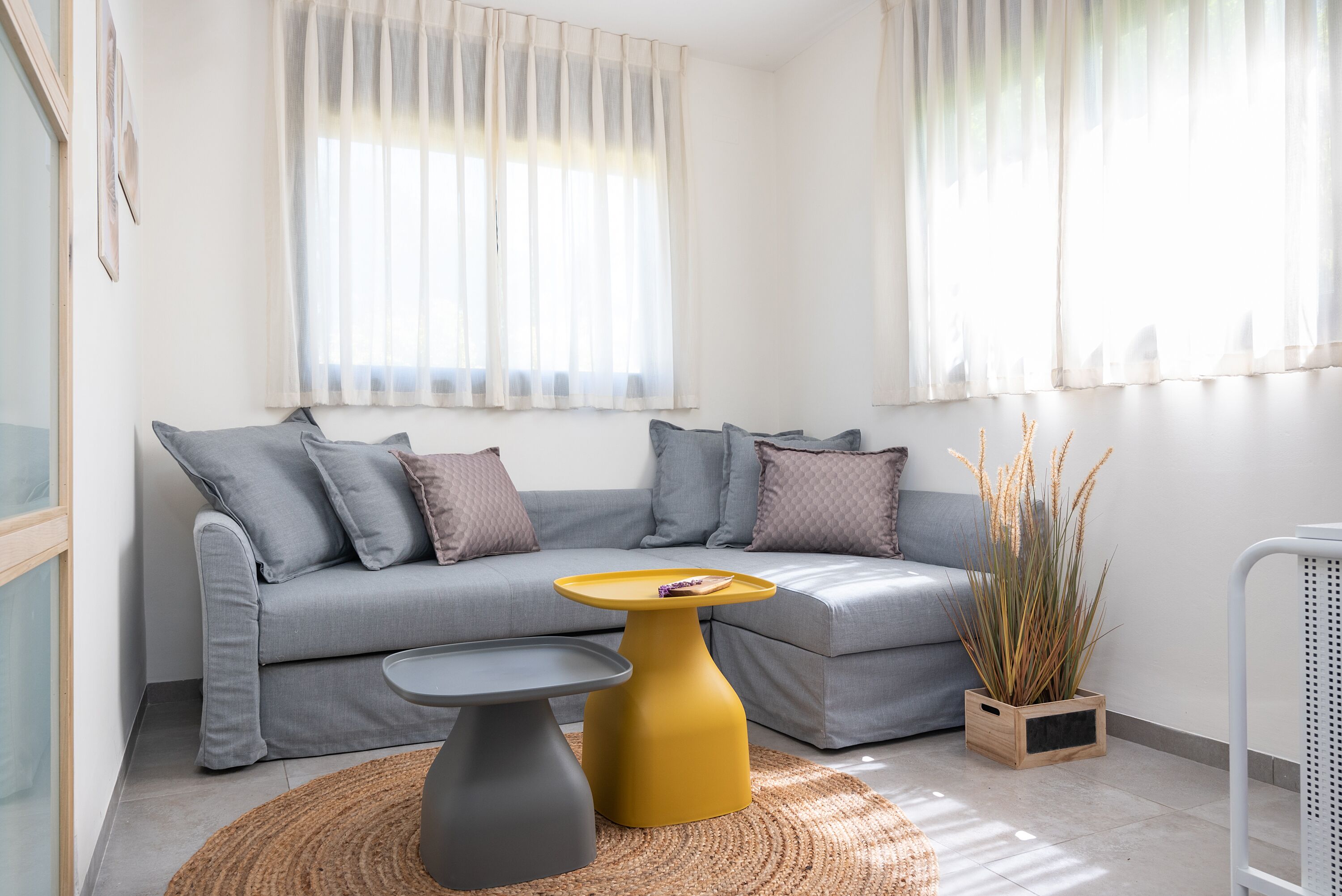 A modern living room with a grey sofa, a yellow coffee table, and a grey side table.