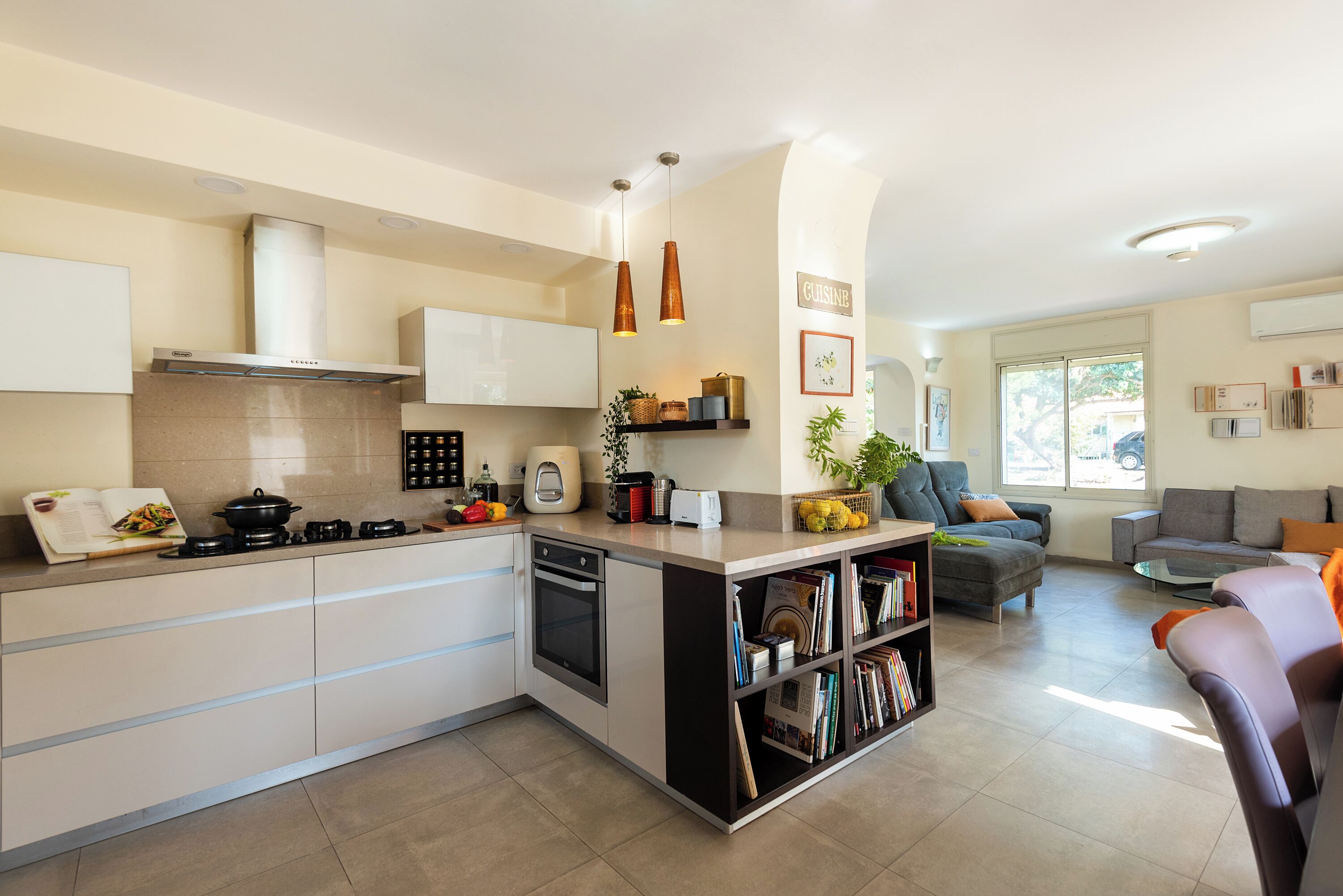 Una cocina moderna con una isla central, electrodomésticos integrados y un rincón de comedor con sofá y mesa de centro.