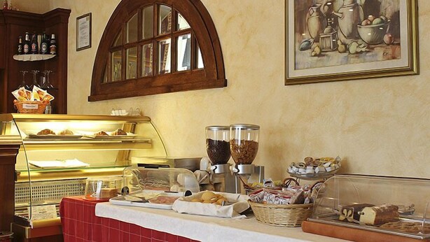 Un bufé de desayuno con diversas opciones de comida, una máquina de café y un cuadro en la pared.