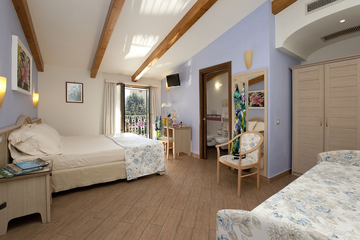 A bedroom with a bed, bedside table, chair, wardrobe, and a small desk with a chair.