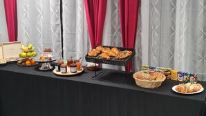 Una mesa de buffet con diversos alimentos, como frutas, pasteles y salsas.
