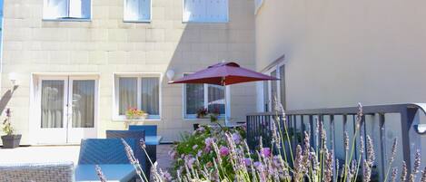 A two-story building with a balcony, outdoor seating, and potted plants.