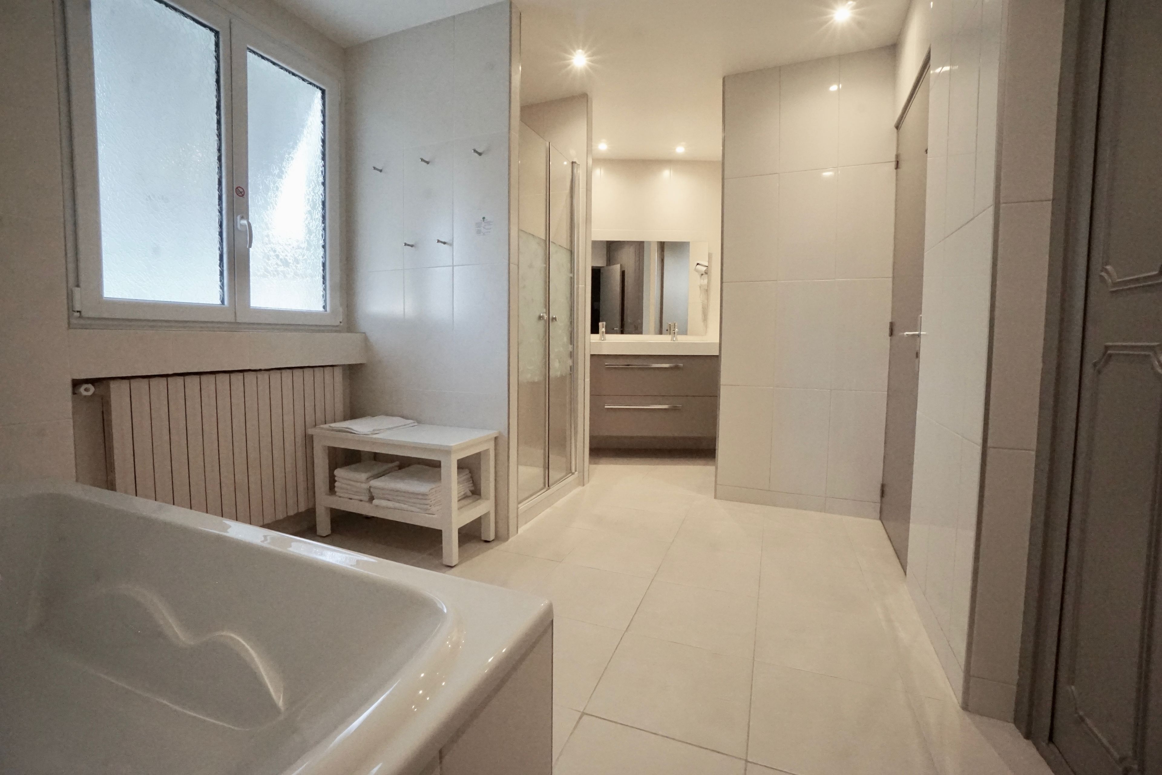 A modern bathroom with a bathtub, a glass shower enclosure, and a vanity with a mirror.