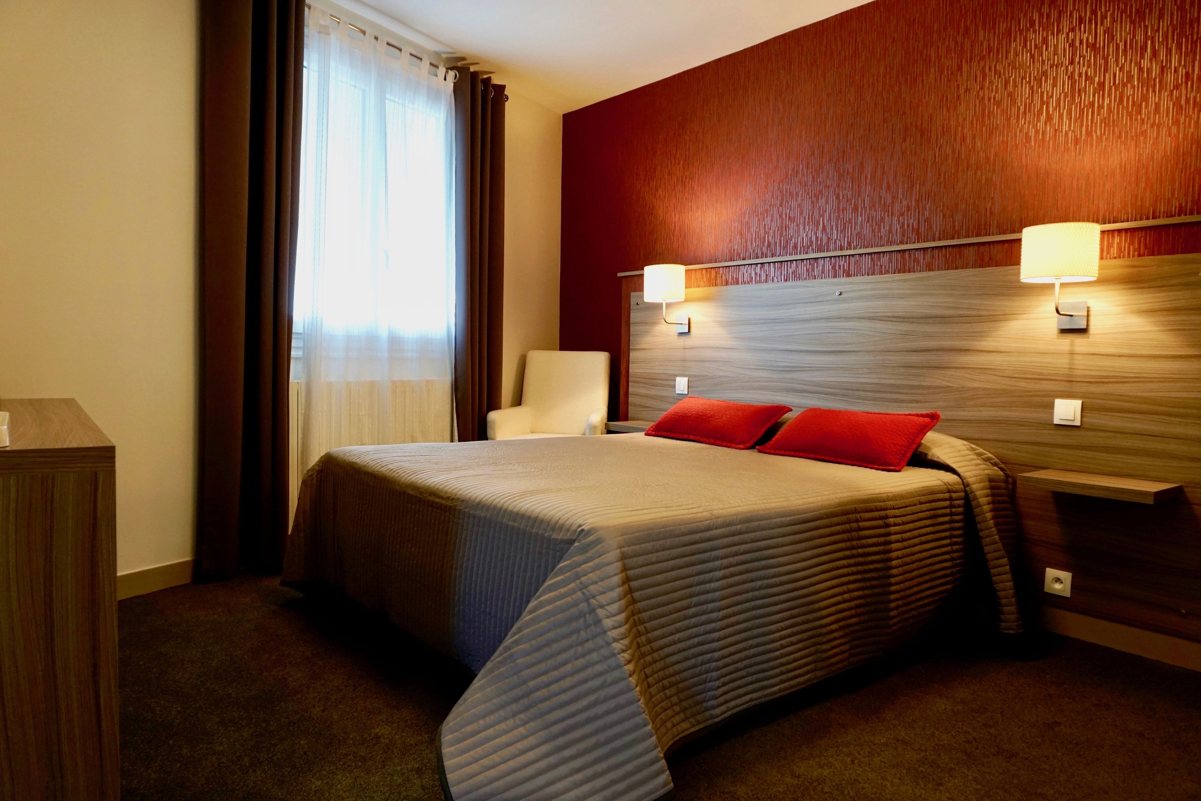 Habitación de hotel con una cama grande, dos lámparas de noche, un cabecero de madera y una mesita de noche.