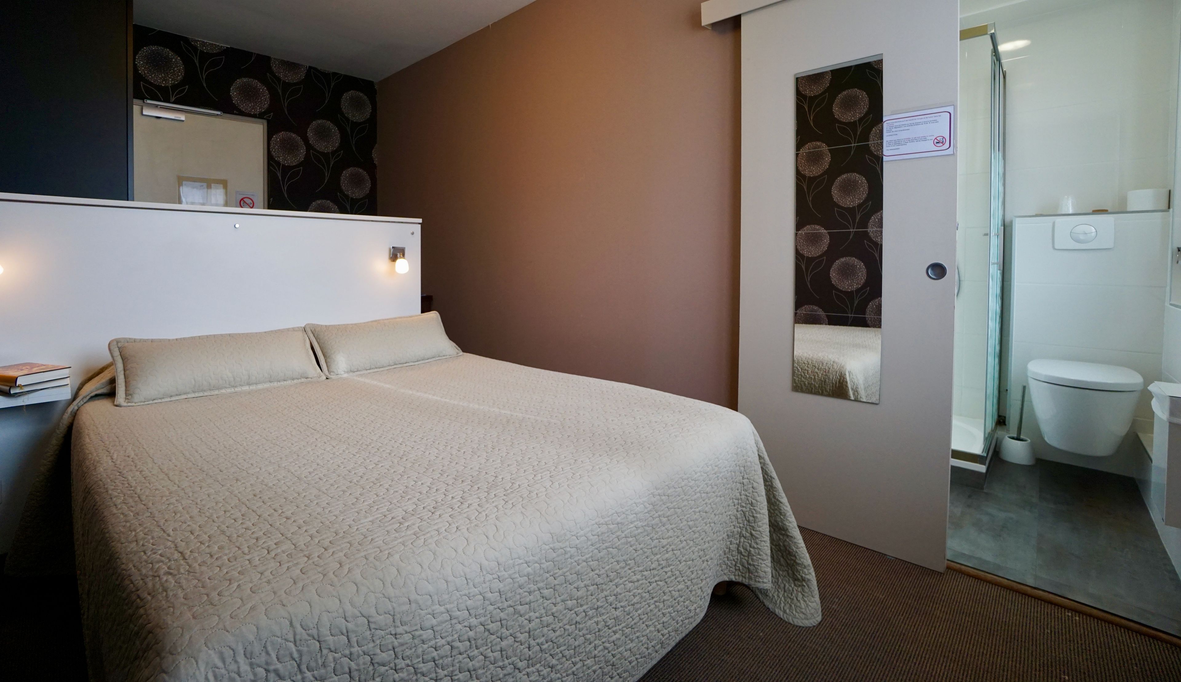 Une chambre d’hôtel avec un lit, une salle de bain et un miroir.
