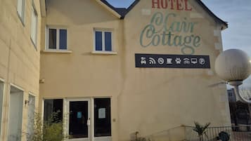 Un hotel llamado "HOTEL Clair Cottage" con un letrero que indica servicios como Wi-Fi, estacionamiento y admisión de mascotas.