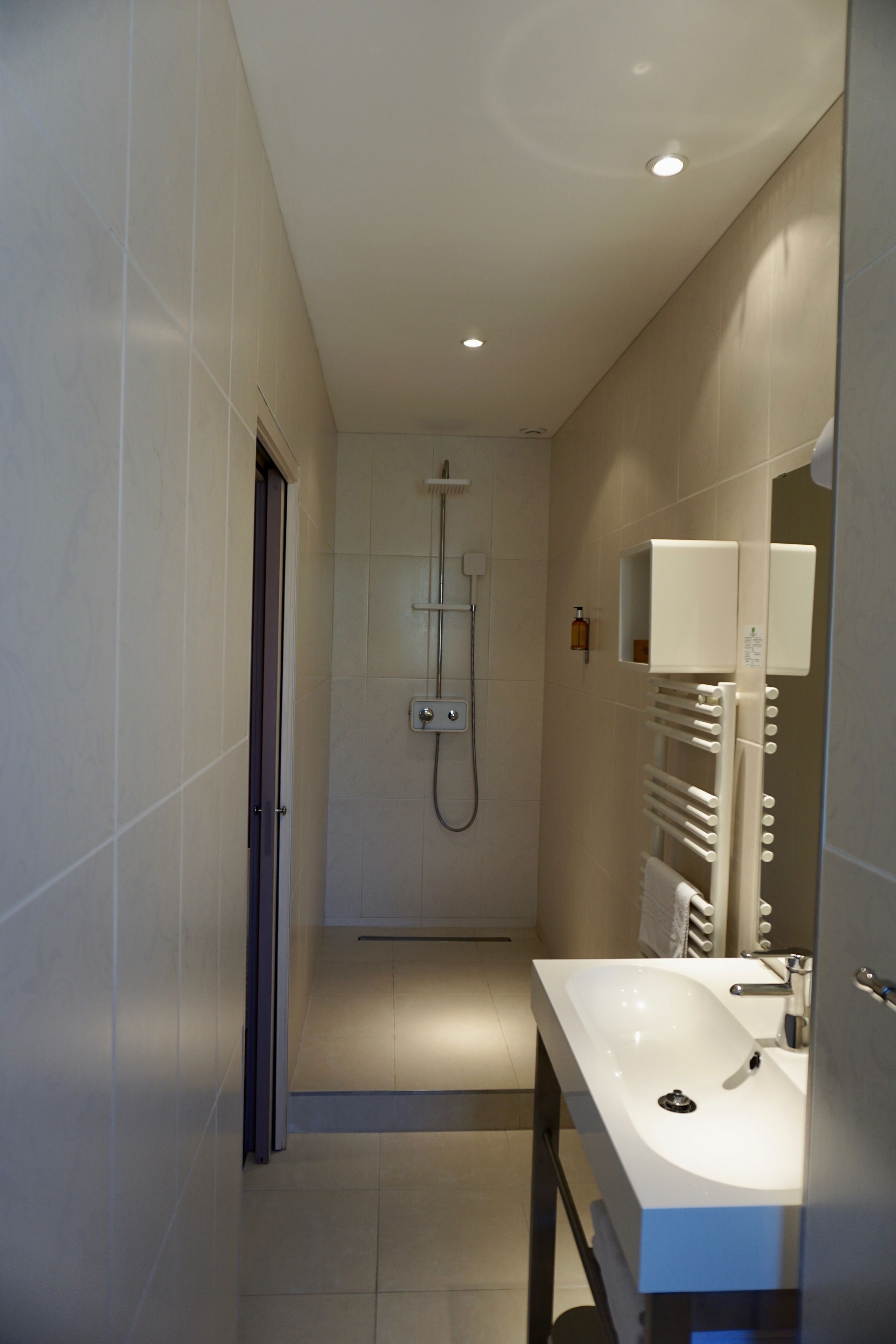 A modern bathroom with a shower, a sink, and a mirror.