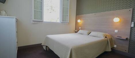 A bedroom with a bed, a window, a wall-mounted light, and a ceiling fan.