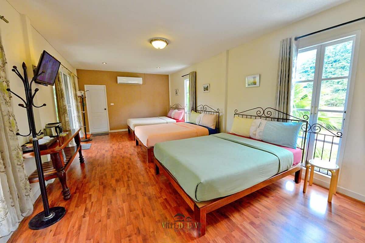 A hotel room with a large bed, a smaller bed, a desk with a chair, a television, and a window with curtains.