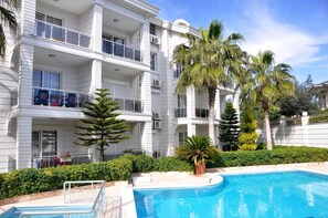 Una piscina al aire libre, sombrillas, sillones reclinables de piscina