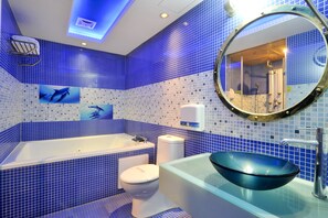 A bathroom with a blue-tiled wall, a white bathtub, a white toilet, and a glass sink with a blue basin. - ZJ Motel (Hsinchu)