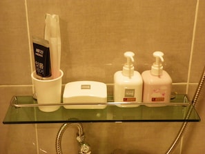 A bathroom shelf with toiletries including a toothbrush, a soap dispenser, and two body wash bottles. - Feliz Casa Guest House (Seoul)