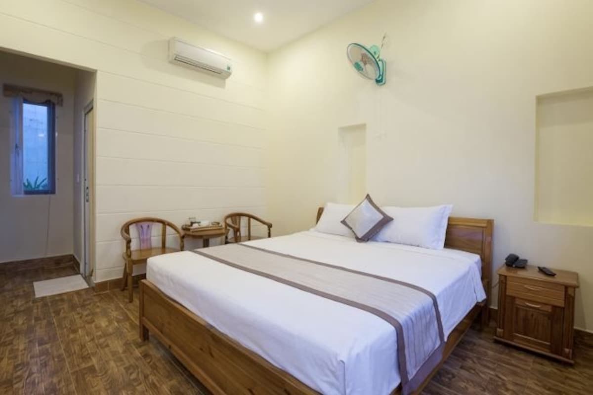 A bedroom with a wooden bed, a bedside table, a chair, and a small desk.