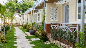 A row of modern, single-story villas with a covered patio, a stone pathway, and lush greenery. - Blue Paradise Resort (Phu Quoc)