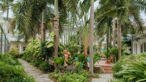 A lush garden with a stone pathway, palm trees, and a statue. - Blue Paradise Resort (Phu Quoc)