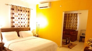A hotel room with a bed, a nightstand, a lamp, a chair, and a small table with a vase of flowers.