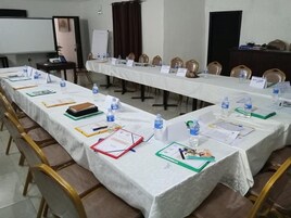 Un salón de conferencias con mesas largas, sillas, tarjetas de identificación, botellas de agua y documentos.
