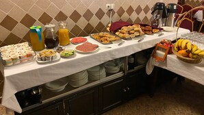 A buffet table with various food items, including bread, pastries, and fruits.