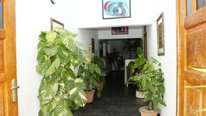 A hallway with potted plants, framed artwork, and a wooden door.