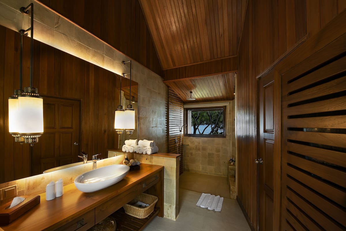 Une salle de bain en bois avec un grand lavabo, un miroir et un porte-serviettes.