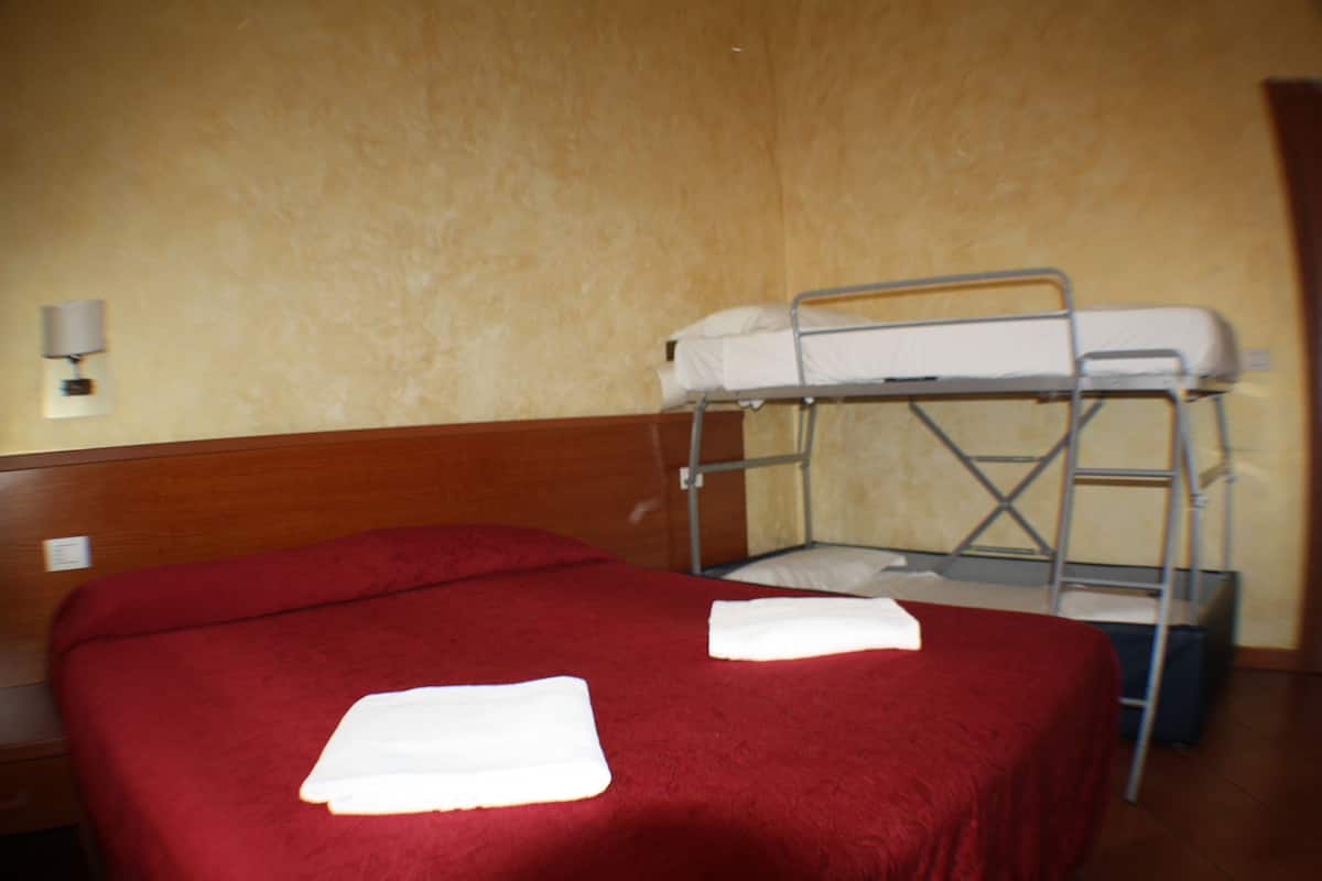 A hotel room with a single bed, a bunk bed, and a wooden headboard.