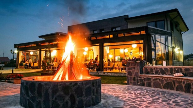 A modern building with a stone fire pit in the foreground.