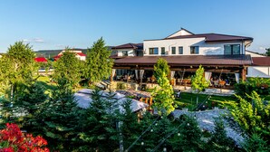 A two-story building with a covered outdoor seating area and a garden.