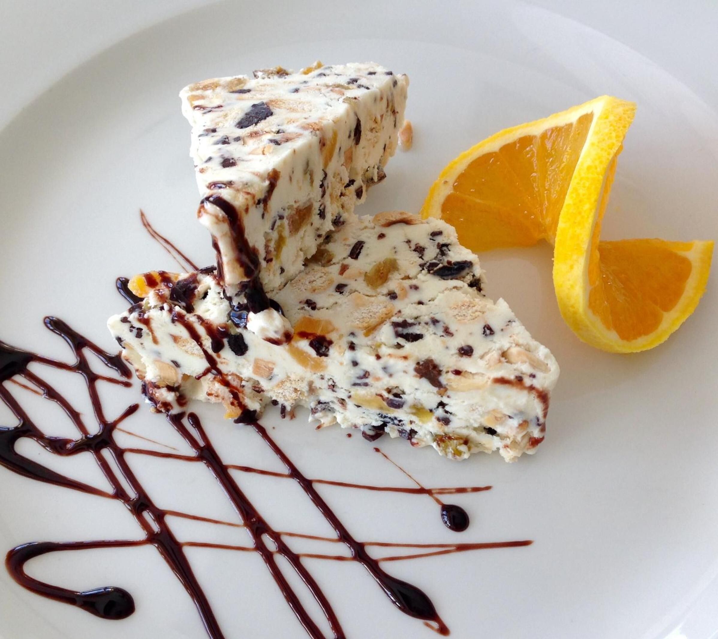 A dessert with chocolate drizzle and a lemon slice on a white plate.