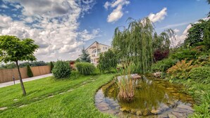 A landscaped garden with a pond, a pathway, and a building in the background.
