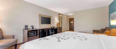 Una habitación de hotel con una cama grande, un escritorio con un televisor de pantalla plana, un microondas y una cafetera.