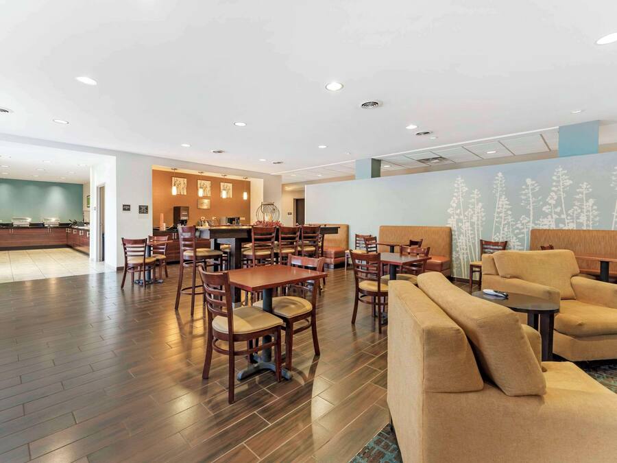 Um hall amplo com várias áreas de estar, uma mesa de recepção e uma cozinha ao fundo.