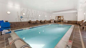 A swimming pool with a tiled edge, a lifeguard chair, and a seating area with chairs. - Sleep Inn & Suites Cumberland - LaVale (Cumberland)