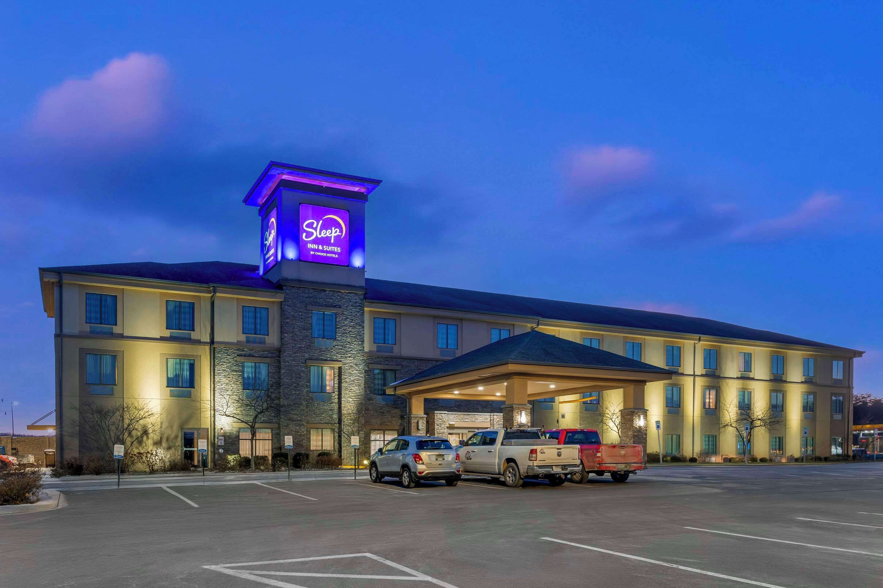 A hotel with a prominent sign, multiple parking spaces, and a well-lit entrance.