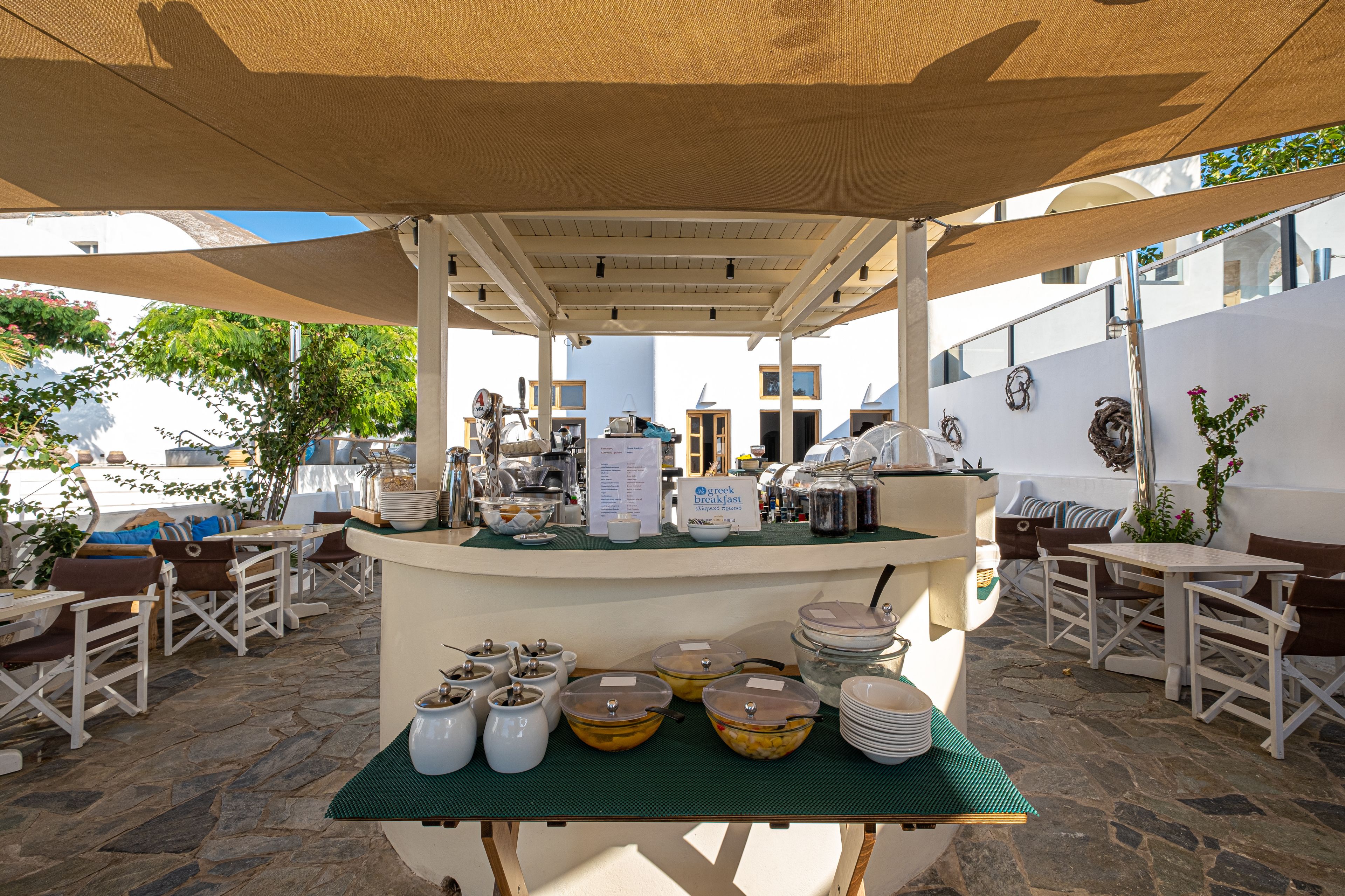 Colazione all'aperto con tavolo a buffet, sedie e ombrelloni.