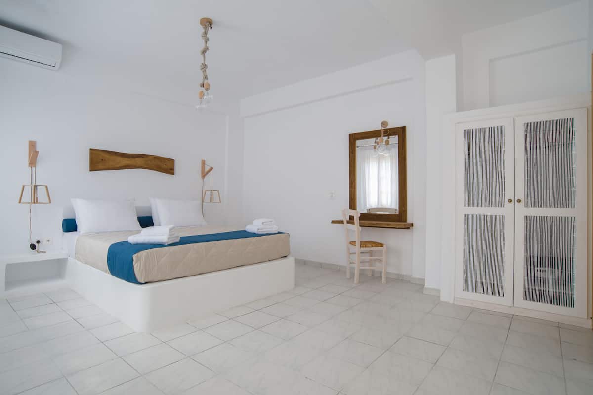 A bedroom with a bed, a desk, a chair, a wardrobe, and a mirror.