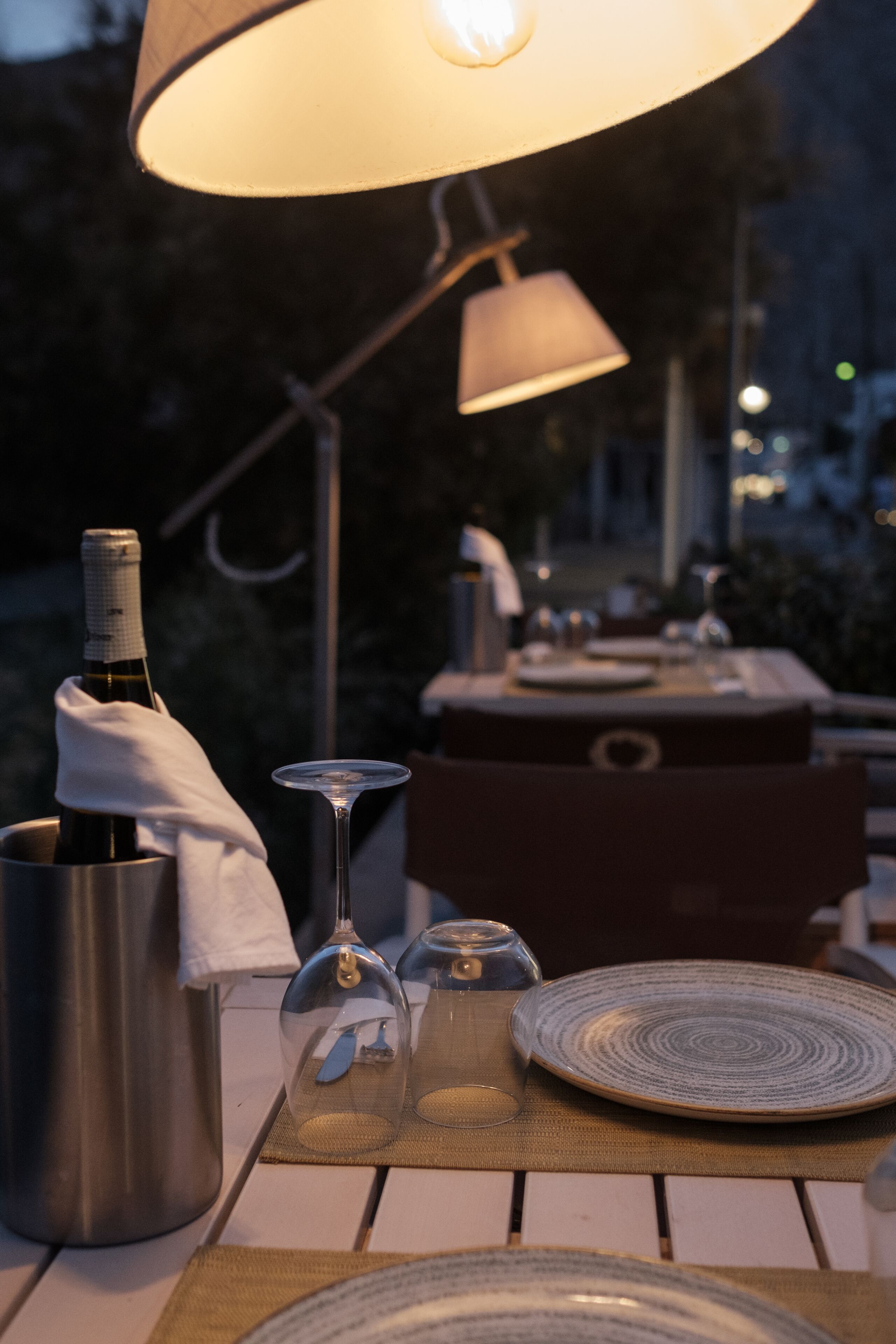 A table set for dining with a bottle of wine, a wine glass, and a candle holder.