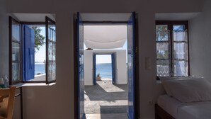 A room with an open door leading to a balcony with a view of the sea. - Santorini Crystal Blue (Santorini)