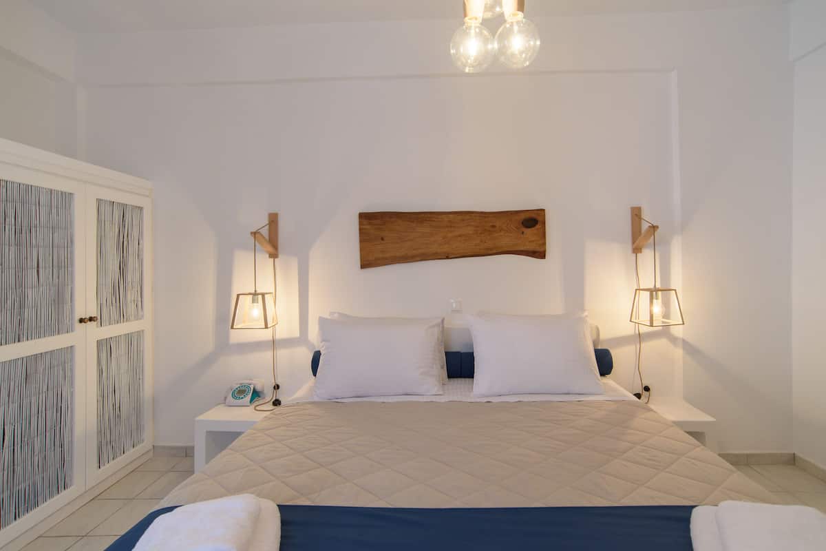 A bedroom with a bed, nightstands, a wooden headboard, and a wardrobe.