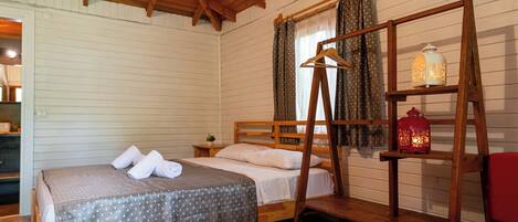 A wooden-framed bed with a polka dot bedspread, a wooden ladder, and a hanging light fixture.