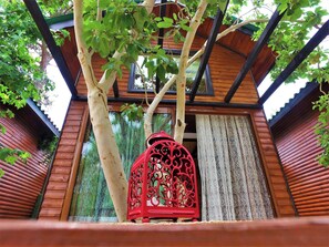 A traditional wooden structure with a red lantern, a tree, and a window. - Koala Bungalows (Kumluca)