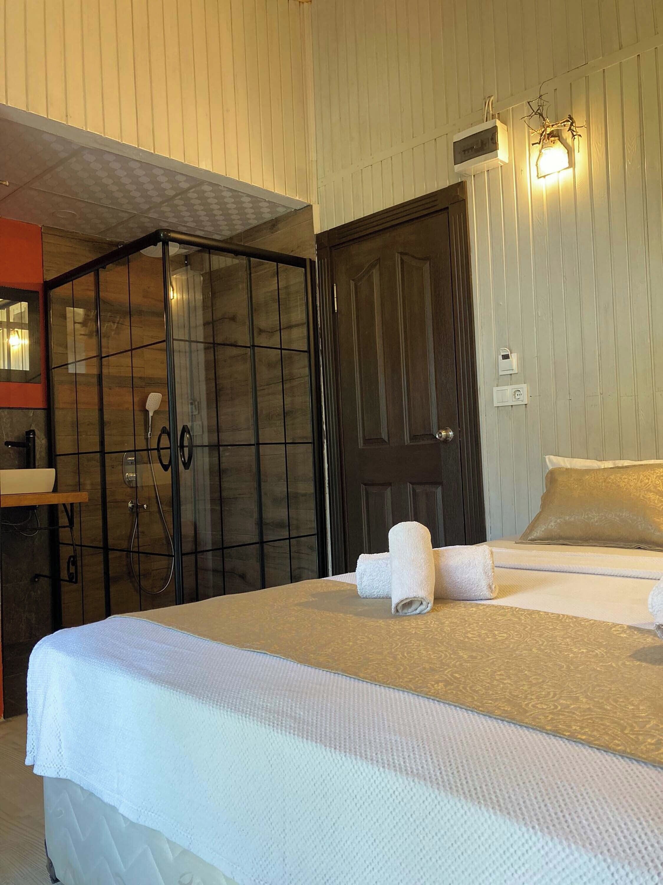A hotel room with a bed, a bathroom with a shower, a wardrobe, and a mirror.