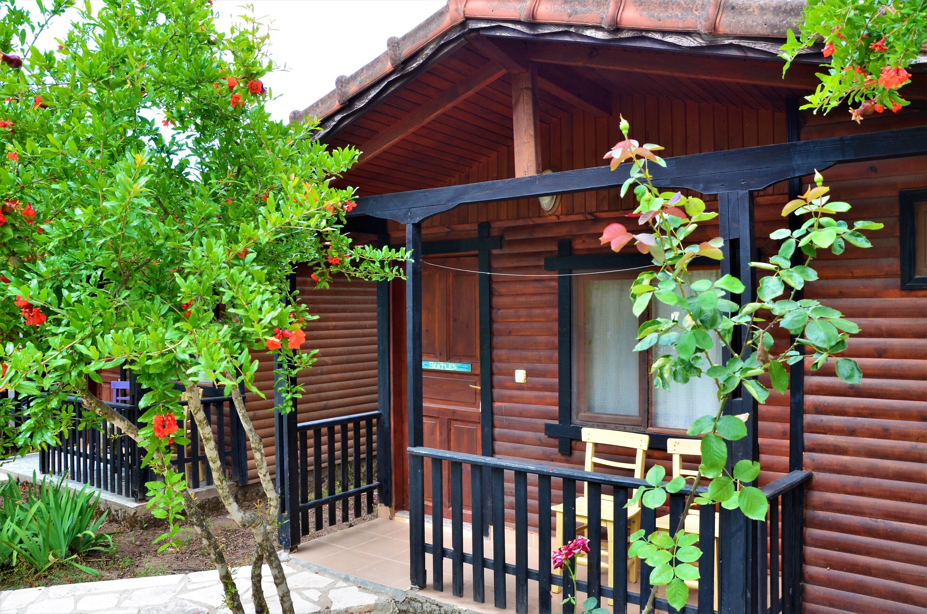 A wooden cabin with a porch, a small table, and a chair.