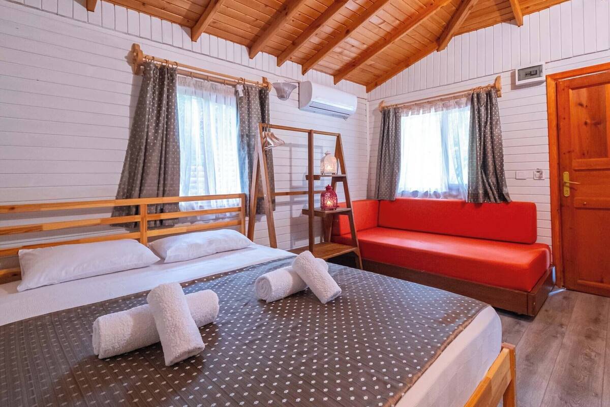 A wooden cabin with a loft-style bedroom, a red sofa, and a ladder.