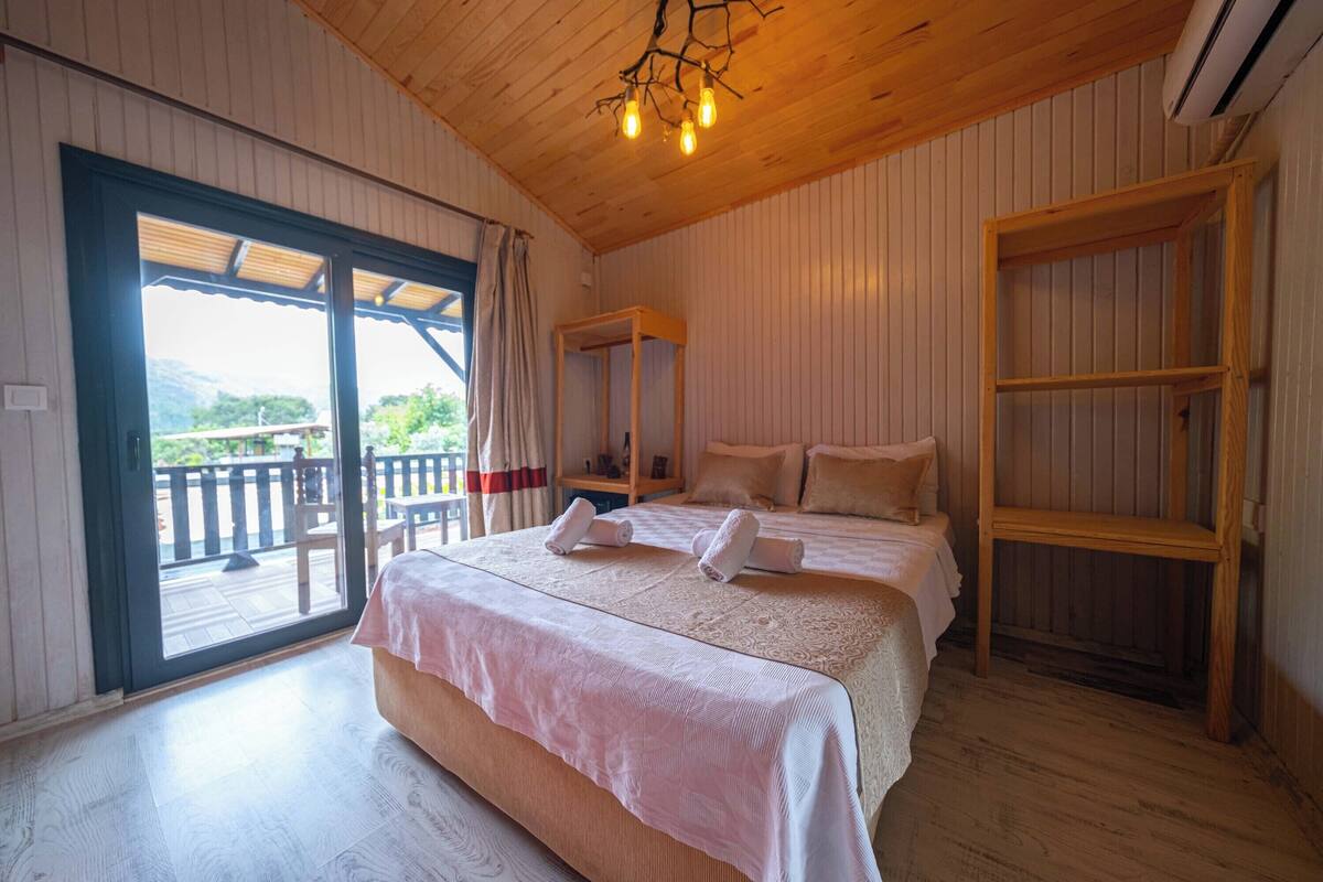 A bedroom with two beds, a wooden ceiling, and a balcony with a view.