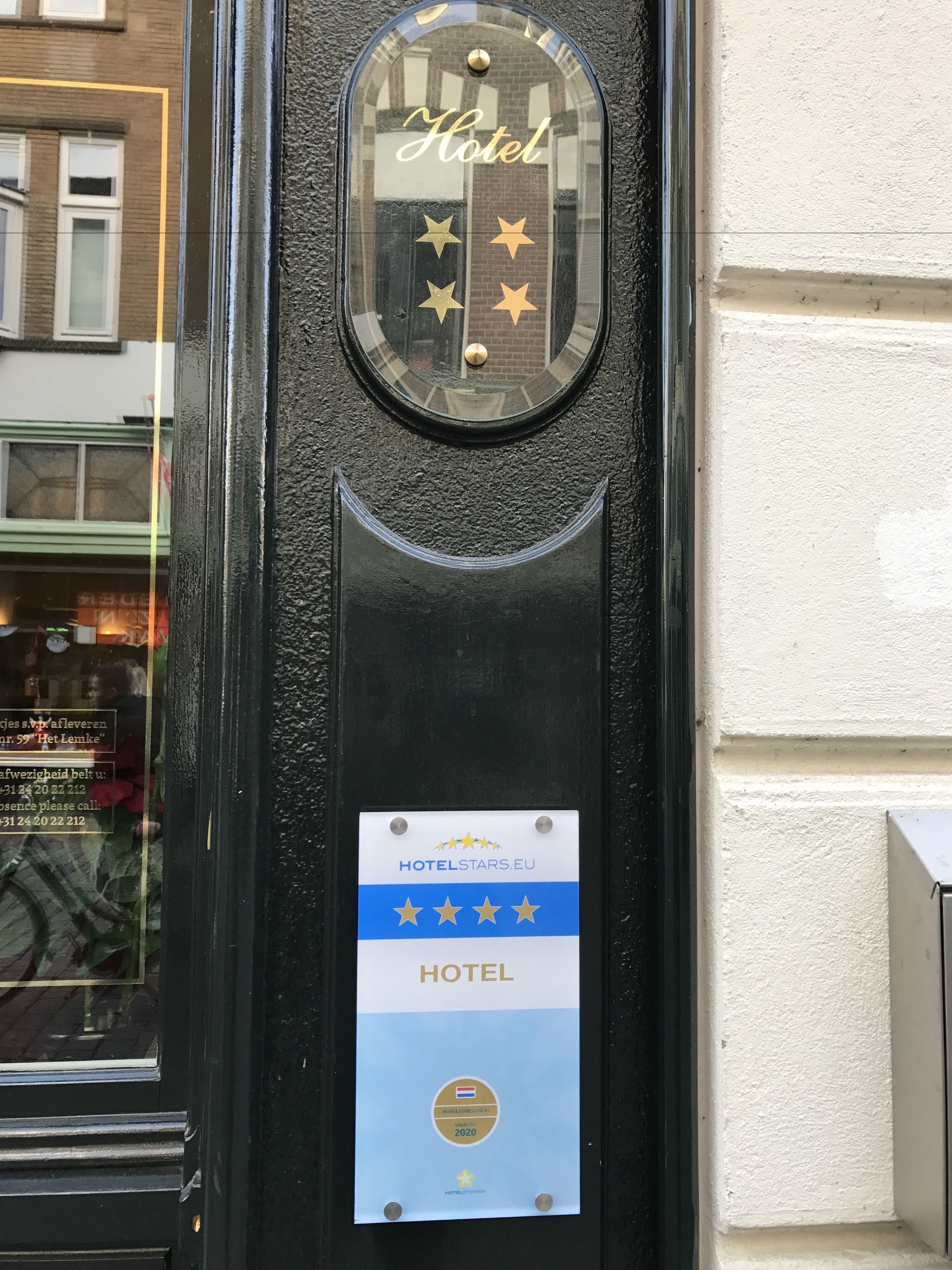 A hotel door with a glass panel displaying the name 'Hotel' and a plaque indicating a four-star rating from HOTELSTARS.EU, valid from 2019 to 2020.